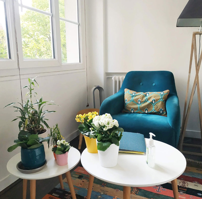 Une pièce avec un fauteuil deux petites tables avec des fleurs pour recevoir les clients en sophrologie
